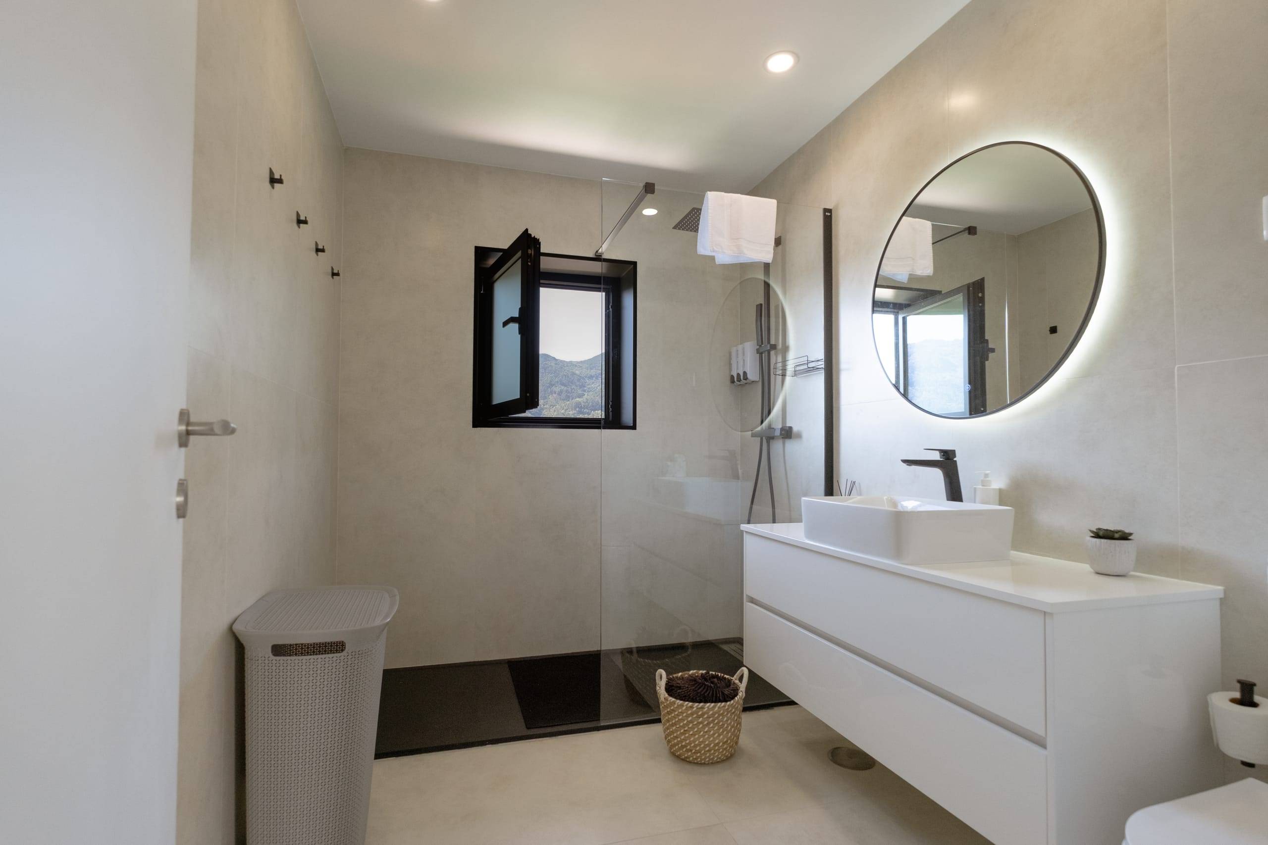 Full bathroom with walk-in shower and round mirror