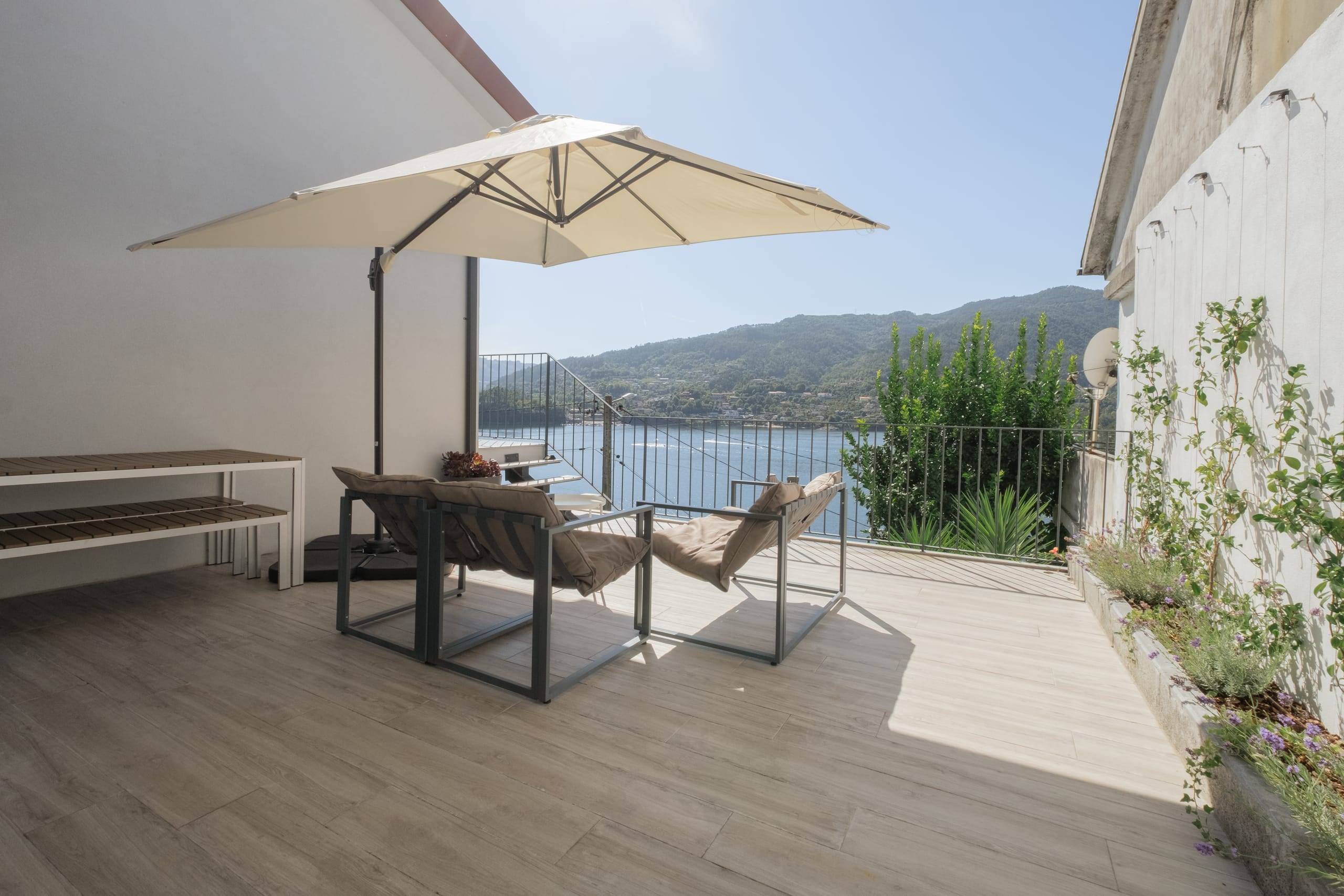 Terrace with lounge chairs, parasol and lake view